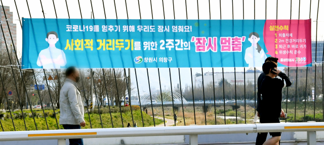 창원시 의창구 창원천 3호교에 사회적 거리두기를 위한 2주간의 ‘잠시 멈춤’ 플래카드가 내걸려 있다./전강용 기자/