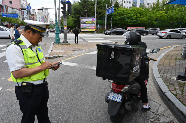 경찰이 신호를 위반하고 교차로를 건넌 오토바이 운전자를 단속하고 있다.