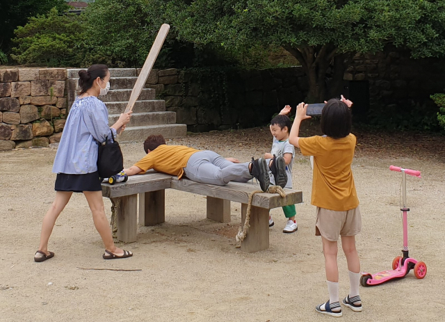 죄수 심문 장면을 묘사한 동헌의 인형들과 곤장 체험을 하는 가족(위에서부터).