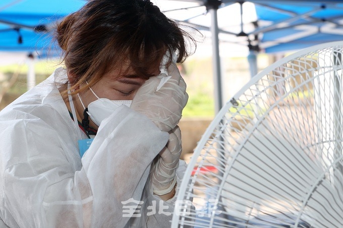 연일 코로나19 확진자 증가와 폭염이 이어지고 있는 20일 전주 화산체육관 선별진료소에서 한 의료진이 선풍기 앞에서 땀을 닦으며 더위를 식히고 있다. 조현욱 기자