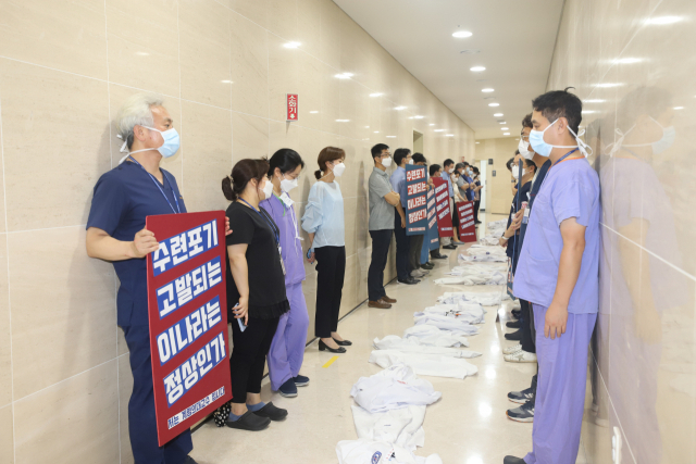 31일 계명대학교 동산병원 교수들이 전공의 근무 여부를 조사하러 나온 보건복지부 실사단에게 피켓시위를 하면서 "가운를 밟고 지나 가라"며 항의의 뜻으로 복도에 가운을 펼쳐 놓았다. 계명대 동산병원 제공