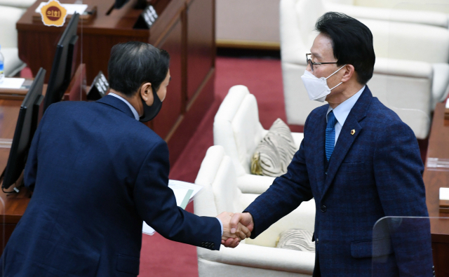 김하용(오른쪽) 경남도의회 의장이 21일 도의회 임시회에서 의장 불신임안이 부결된 후 성낙인 의원과 악수하고 있다./김승권 기자/