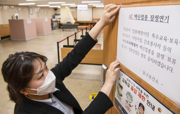 8일 오전 광주시 동구보건소에 마련된 코로나19 백신 접종실 입구에 보건소 직원이 아스트라제네카 백신 접종 연기 안내문을 붙이고 있다. /최현배 기자choi@kwangju.co.kr