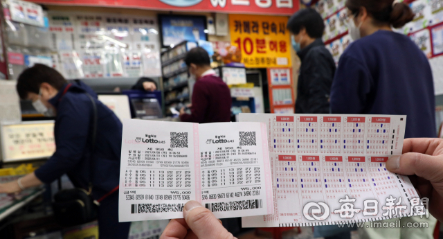 8일 대구 한 복권방에서 고객이 로또 번호를 하나의 패턴으로 모두 고정해 10장을 같은 번호로 구입한 로또복권과 용지를 보여주고 있다. 정운철 기자 woon@imaeil.com