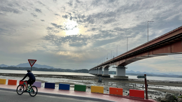 경남 사천 무지갯빛 해안도로. 일곱 빛깔 연석과 사천대교, 사천만 갯벌이 어우러진 풍경을 볼 수 있다.