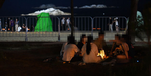 코로나19 4차 유행으로 수도권에 이어 강릉에 최근 확진자가 급증하며 거리 두기를 4단계로 격상된 가운데 지난 18일 밤 강릉 경포해수욕장 방역 팬스 인근에서 관광객들이 삼삼오오 모여 음식물을 먹고 있다. 강릉시는 방역을 위해 방역 팬스를 치고 야간 취식 금지와 마스크 착용이 의무화하고 있다. 강릉=권태명기자