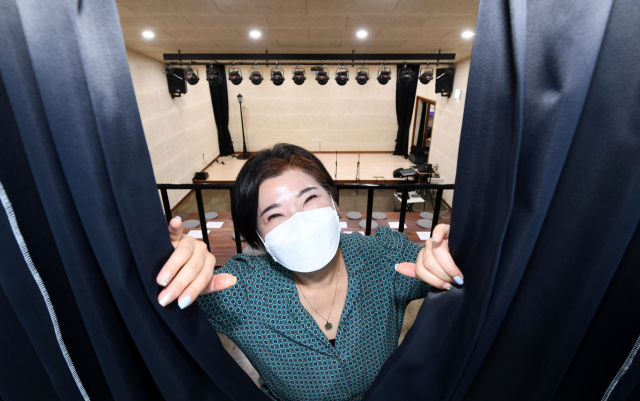 곽지수 봉황예술극장 대표가 무대 입구 커튼 사이로 포즈를 취하고 있다./성승건 기자/