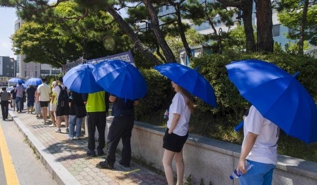코로나19 확산세가 이어지고 있는 가운데 29일 광주 광산구 선별진료소에서 시민들이 구청에서 제공한 우산으로 햇볕을 가리고 줄 서 있다./최현배 기자choi@kwangju.co.kr