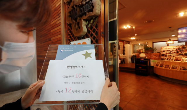 사회적 거리 두기가 조정된 첫날인 18일 오후 부산 해운대구 한 식당 출입구에 ‘접종 완료자 6명 포함 10명, 밤 12시까지 영업’ 안내문이 붙어 있다. 김경현 기자 view@
