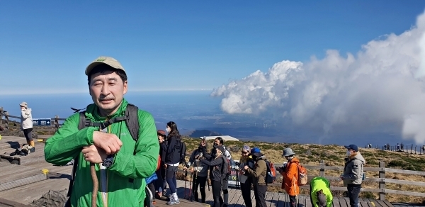 한라산 정상에 오른 이영철 작가. 동능 주변은 정상에 오른 기쁨을 만끽하는 등반객들로 활기가 넘쳐난다. 백록담 표지석 앞에는 탐방객들이 줄지어 서있어 왁자지껄하다.