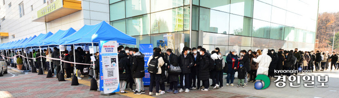 1일 오전 수원시 장안구보건소 코로나19 임시 선별진료소에서 시민들이 검사를 받기 위해 길게 줄 서 기다리고 있다. 단계적 일상회복을 위해 사회적 거리두기 완화를 시행한 지 한 달이 되는 이날 0시 기준 코로나19 신규 확진자는 5천123명을 기록해 코로나19 팬데믹 이후 최대를 기록했다. 2021.12.1 /임열수기자 pplys@kyeongin.com