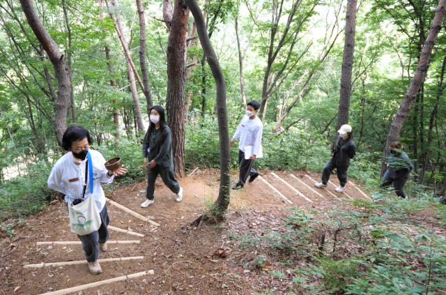 양산 대운산 자락에 있는 양방항노화 힐링서비스 체험관 ‘숲애서’ 체험자들이 숲 치유길을 걸으며 명상을 하고 있다./숲애서/