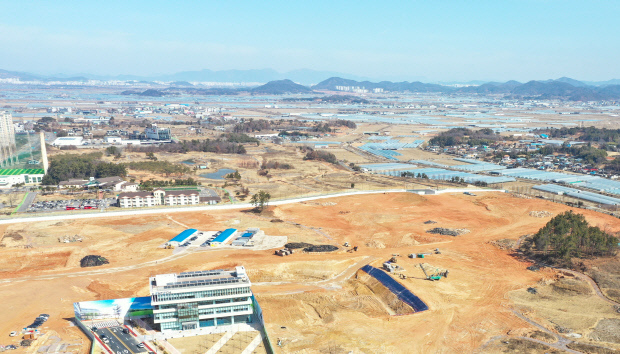 2일 나주혁신도시에 문을 연 한국에너지공대의 개교 핵심시설(사진 앞 건물)과 공사 중인 학교 부지 뒤편으로 부영주택 측이 아파트 5300가구 건설을 위해 토지 용도변경을 추진 중인 나주 혁신도시 부영골프장 잔여부지(호수 주변 35만㎡·빨간 선 안쪽)가 보인다. /최현배 기자 choi@kwangju.co.kr