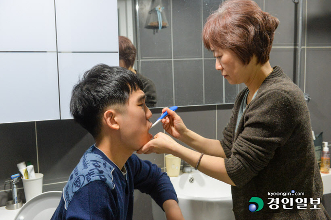 정미경 씨가 호흡이 고르지 못해 양치를 혼자 할 수 없는 아들에게 양치를 시켜주고 있다. 2022.3.17 /김도우기자 pizza@kyeongin.com