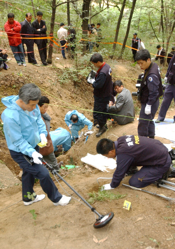 2002년 개구리소년 확인을 위해 국과수 감식팀들이 유해발굴을 벌이던 중 탄두와 총알이 나오자 감식팀들이 금속탐지기를 동원, 다른 총알을 찾고 있다. 매일신문 DB