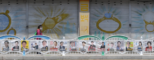 한 시민이 30일 오후 창원시 의창구 도계동 도로변에 부착된 선거벽보 옆을 지나고 있다./김승권 기자/
