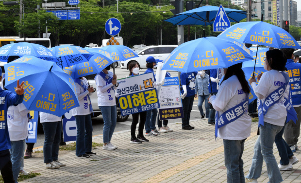 제8회 전국동시지방선거를 이틀 앞둔 30일 오후, 광주 광산구 신가동 한 교차로에서 더불어민주당 선거운동원들이 파란우산을 들고 지지를 호소하고 있다. /나명주기자mjna@kwangju.co.kr