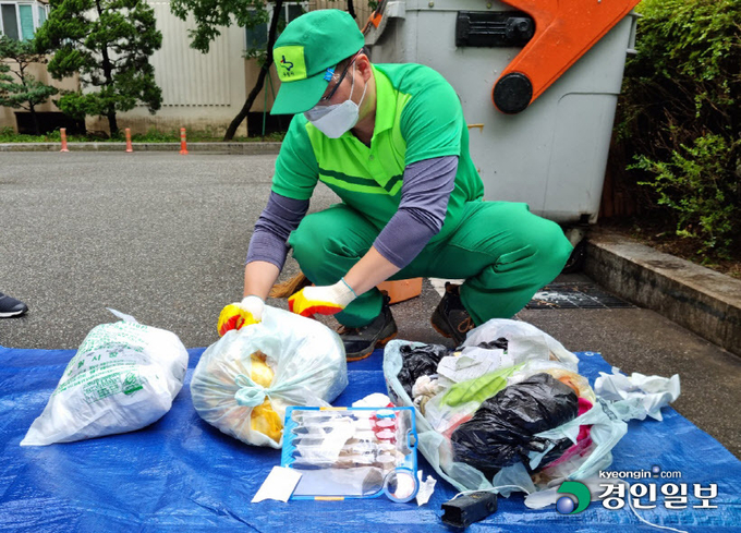 지난 11일 오전 수원시 장안구 조원2동의 한 아파트단지에서 이뤄진 샘플링(표본검사) 작업 중에 환경미화원이 종량제 봉투를 뜯어 내용물을 확인하고 있다. 2022.8.11 /배재흥기자 jhb@kyeongin.com