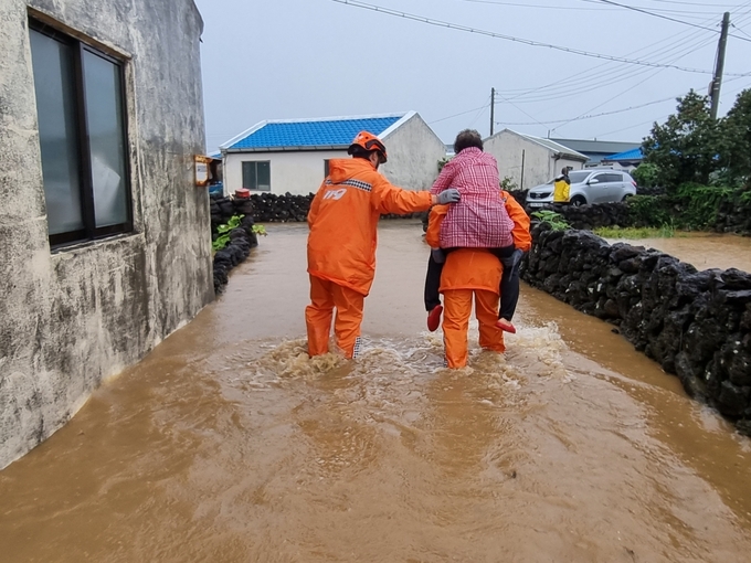 제11호 태풍 힌남노의 영향으로 많은 비가 내리면서 4일 서귀포시 대정읍 영락리 일대 곳곳이 침수돼 주민이 소방관에게 업혀하고 있다. 사진=서부소방서 제공