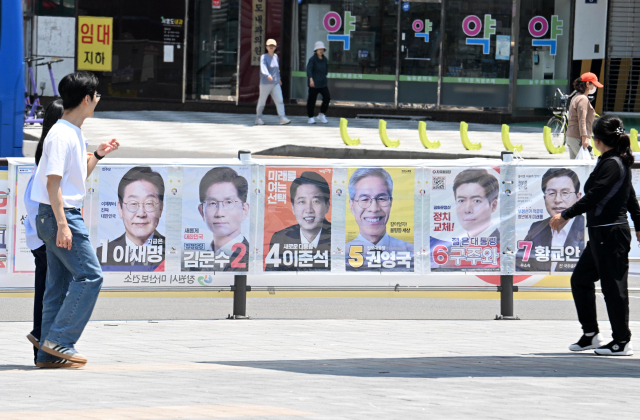 제21대 대통령 선거를 아흐레 앞둔 25일 창원시 마산합포구 월영광장에서 시민들이 선거 벽보를 흘깃 쳐다보고 발걸음을 옮기고 있다./성승건 기자/