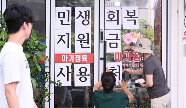 6일 오후 창원시 성산구 상남동의 한 정육점 주인이 민생회복 지원금 사용 관련 안내문을 입구에 붙이고 있다./전강용 기자/