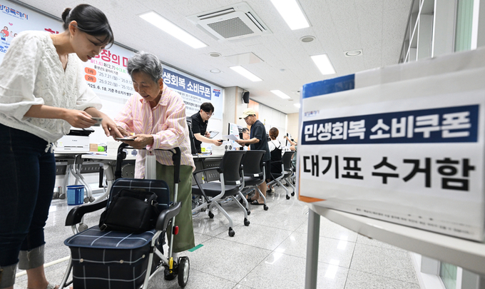 민생회복 소비쿠폰 1차 신청 첫날인 21일 오전 화성시 병점 1동 행정복지센터에서 한 어르신이 소비쿠폰을 발급받은 후 사용방법을 설명 듣고 있다. 2025.7.21 /임열수기자 pplys@kyeongin.com